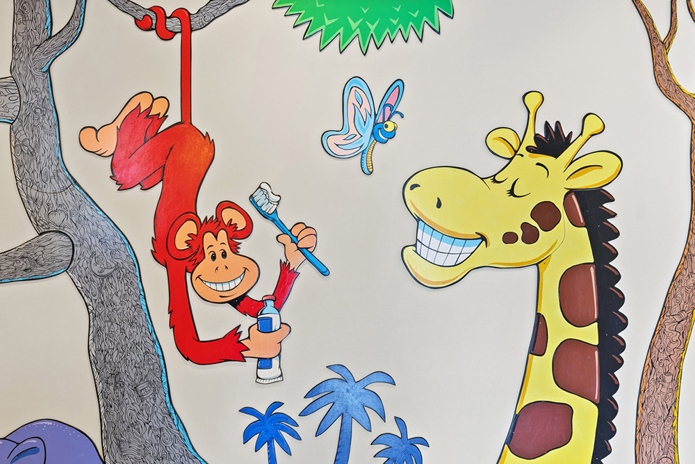Colorful children's mural featuring playful animals including a giraffe and monkey in a jungle setting with trees.