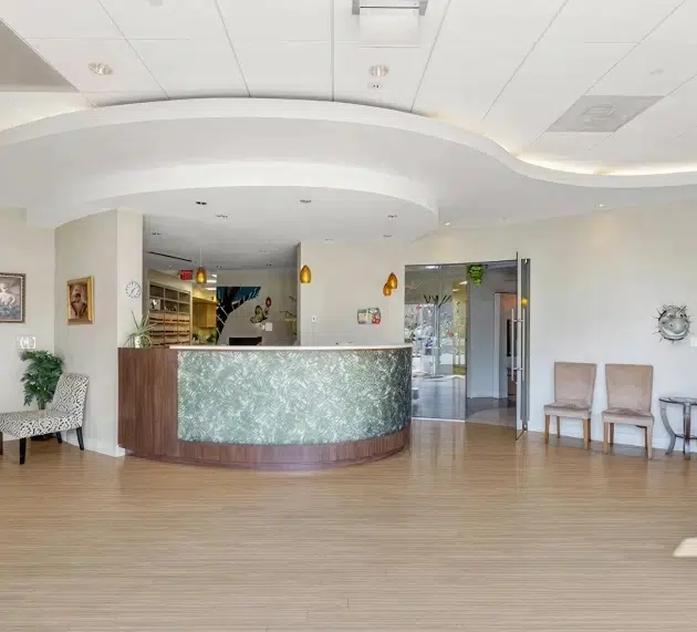 Modern pediatric dental office reception area with curved desk and waiting seating